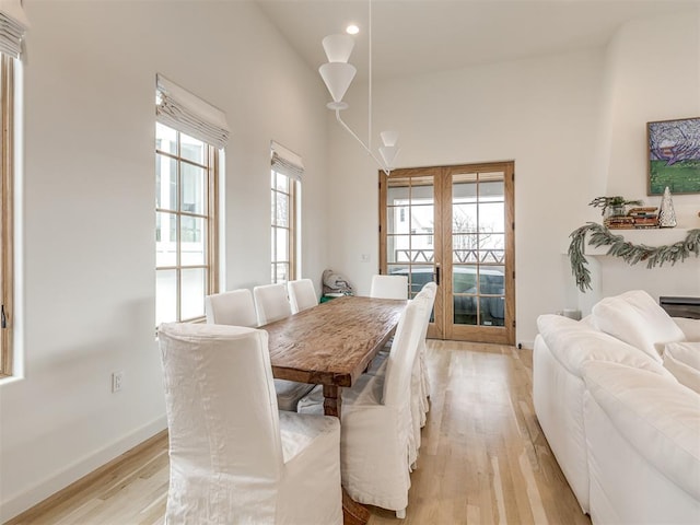 dining area with vaulted ceiling, french doors, and light hardwood / wood-style flooring