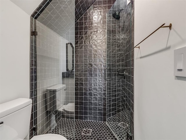 bathroom featuring toilet and a shower with shower door