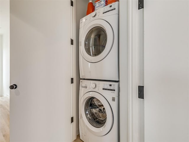 washroom with stacked washer / drying machine and wood-type flooring