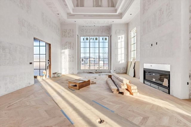 miscellaneous room featuring a high ceiling, light parquet flooring, and a raised ceiling