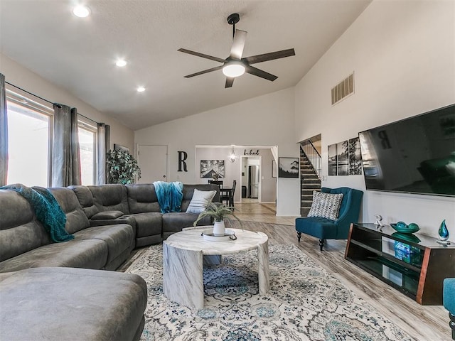 living room featuring ceiling fan, light hardwood / wood-style flooring, and lofted ceiling