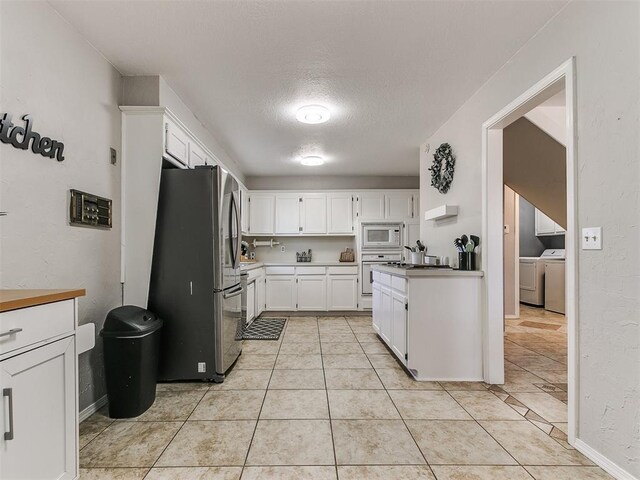 kitchen featuring white cabinetry, independent washer and dryer, a textured ceiling, white appliances, and light tile patterned floors