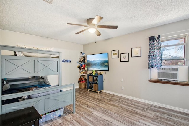 interior space featuring ceiling fan, cooling unit, wood-type flooring, and a textured ceiling