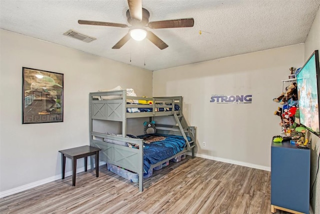 bedroom with ceiling fan, hardwood / wood-style floors, and a textured ceiling