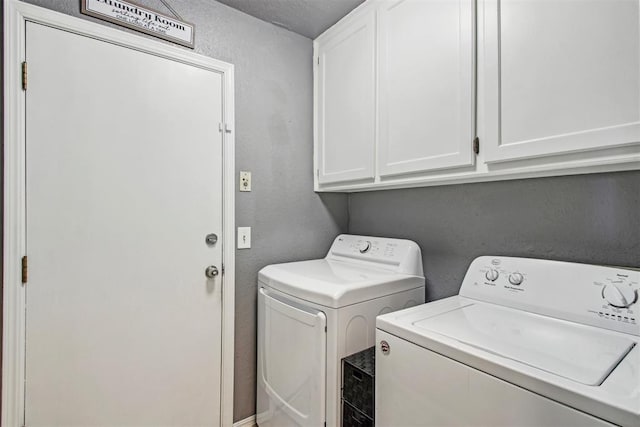 laundry area with cabinets, a textured ceiling, and separate washer and dryer