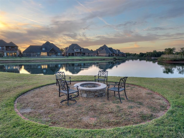 patio terrace at dusk with a yard, a water view, and a fire pit