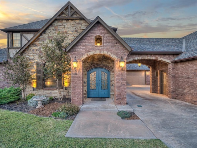 exterior entry at dusk featuring a garage and french doors