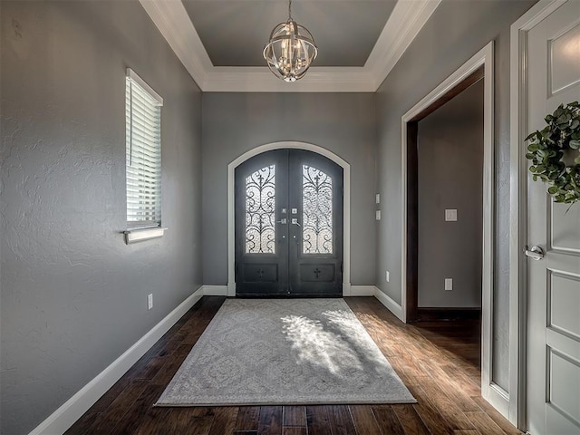 foyer entrance featuring french doors, a tray ceiling, crown molding, an inviting chandelier, and dark hardwood / wood-style floors