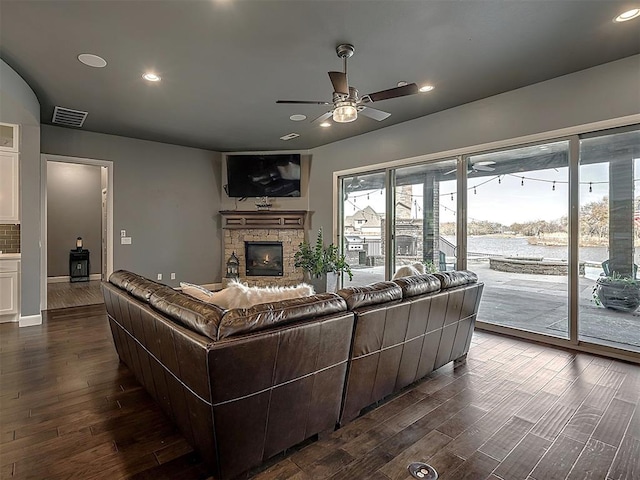 living room featuring ceiling fan, a fireplace, and dark hardwood / wood-style floors