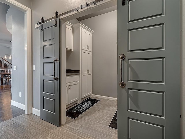 kitchen with a barn door, light hardwood / wood-style flooring, and white cabinetry