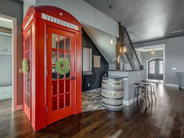 bar with french doors, pendant lighting, vaulted ceiling, and dark wood-type flooring
