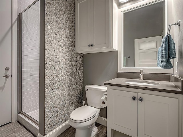 bathroom with wood-type flooring, vanity, toilet, and a shower with door