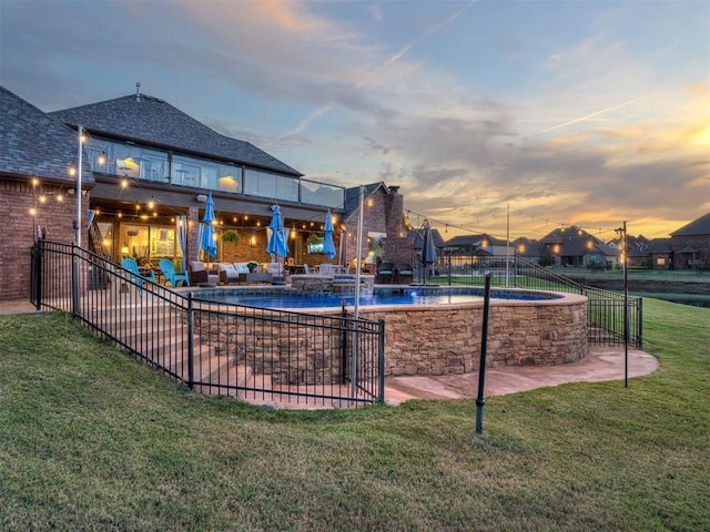 pool at dusk with pool water feature, a patio area, an outdoor hangout area, and a yard