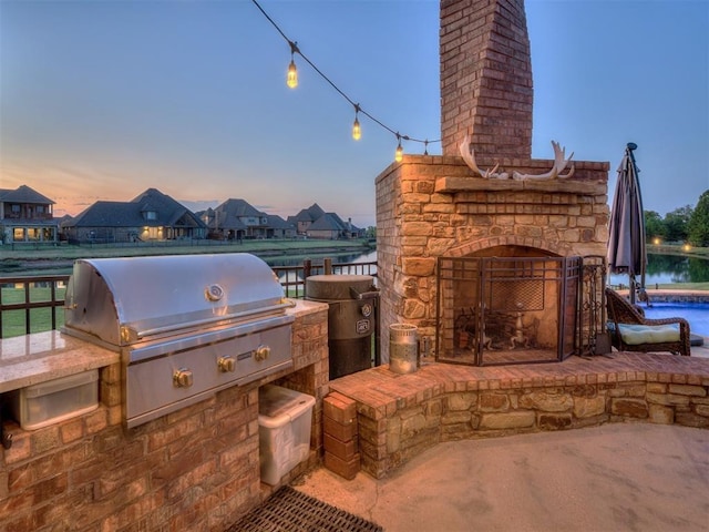 patio terrace at dusk featuring area for grilling and a water view