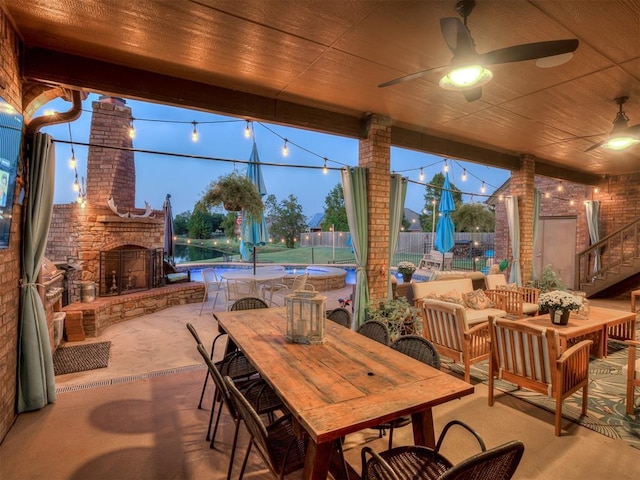 patio terrace at dusk featuring an outdoor living space with a fireplace, ceiling fan, and a fenced in pool
