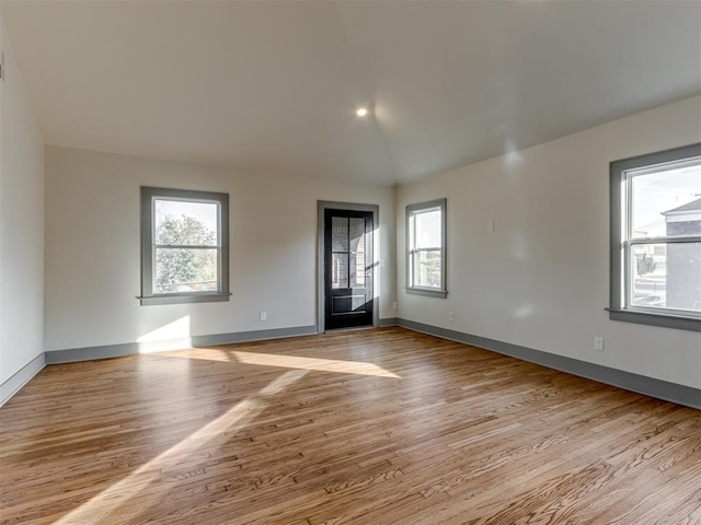 unfurnished room with plenty of natural light, light wood-type flooring, and lofted ceiling