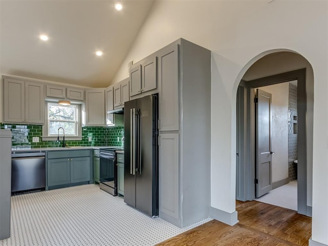 kitchen with gray cabinetry, sink, light hardwood / wood-style flooring, vaulted ceiling, and appliances with stainless steel finishes