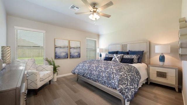 bedroom featuring a ceiling fan, wood finished floors, visible vents, and baseboards