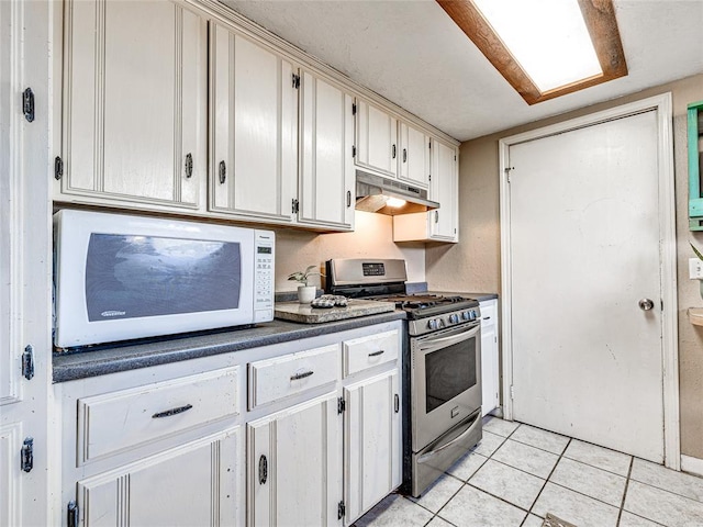 kitchen with light tile patterned flooring, stainless steel range with gas stovetop, and white cabinets