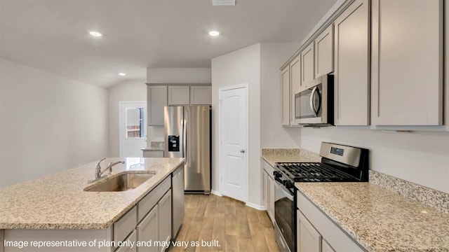 kitchen with an island with sink, gray cabinets, stainless steel appliances, and a sink