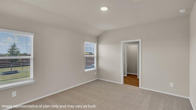 unfurnished bedroom with light carpet, lofted ceiling, and baseboards