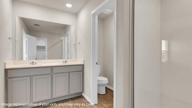 full bathroom with toilet, wood finished floors, visible vents, a sink, and double vanity