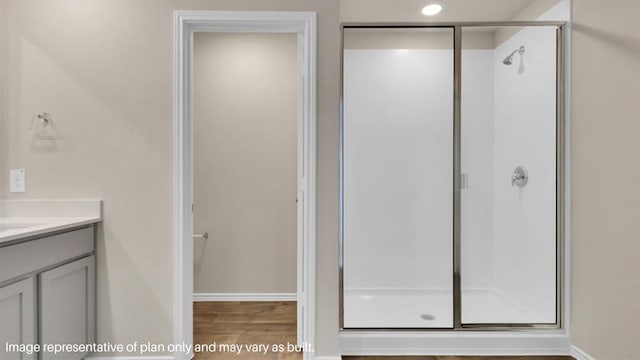 full bathroom featuring a shower stall, baseboards, wood finished floors, and vanity