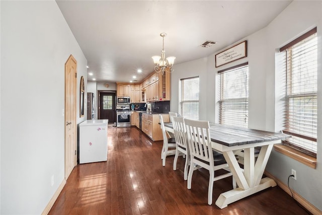 dining room featuring a wealth of natural light, dark hardwood / wood-style flooring, sink, and an inviting chandelier