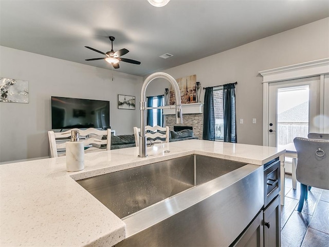 kitchen featuring ceiling fan, light stone countertops, and sink