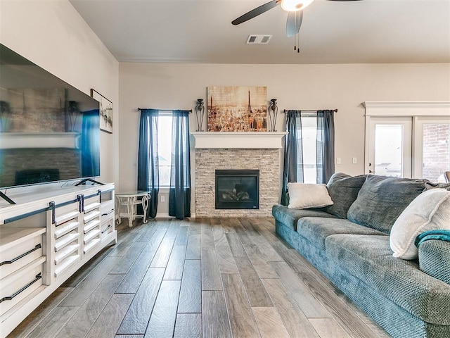 living room with a stone fireplace, a wealth of natural light, and wood-type flooring