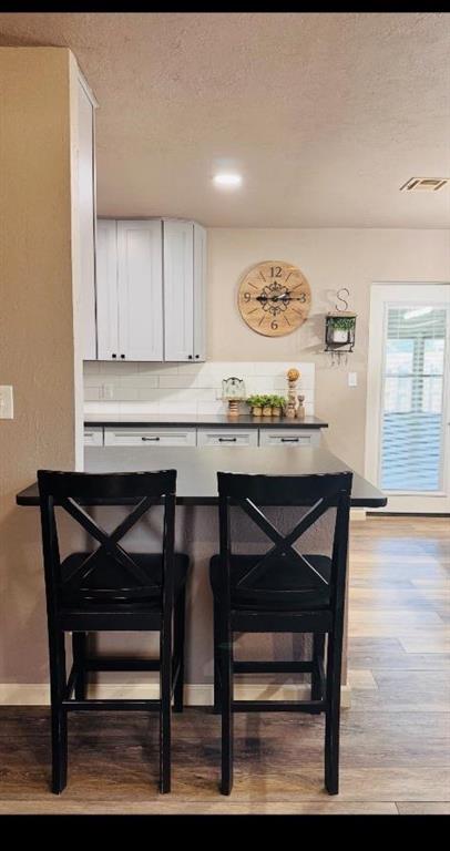 kitchen featuring a textured ceiling, light wood-type flooring, and white cabinetry