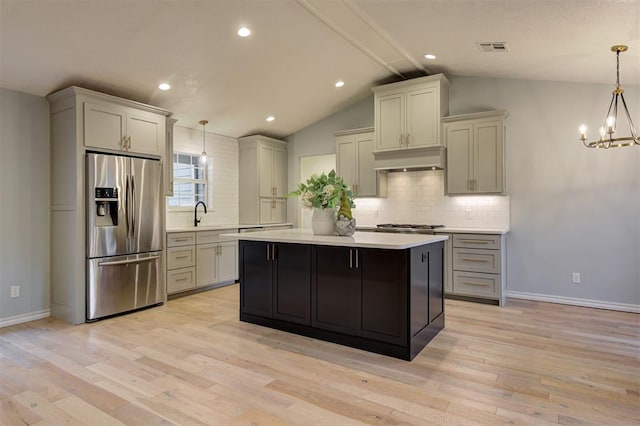 kitchen with lofted ceiling with beams, hanging light fixtures, stainless steel appliances, and light wood-type flooring