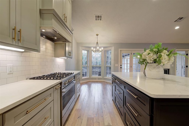 kitchen with light stone counters, stainless steel range, decorative light fixtures, light hardwood / wood-style flooring, and a chandelier