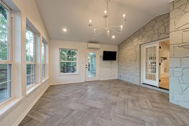 unfurnished sunroom featuring a wall mounted air conditioner, a chandelier, vaulted ceiling, and plenty of natural light