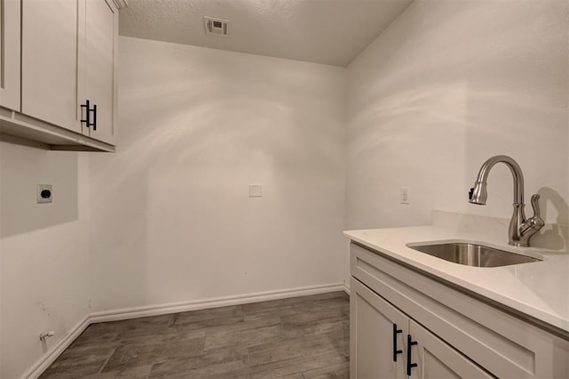 clothes washing area with dark hardwood / wood-style flooring, sink, cabinets, and hookup for an electric dryer