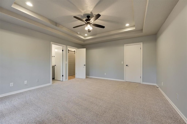 carpeted empty room with a tray ceiling and ceiling fan