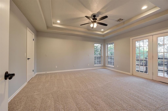 carpeted empty room with a raised ceiling and ceiling fan