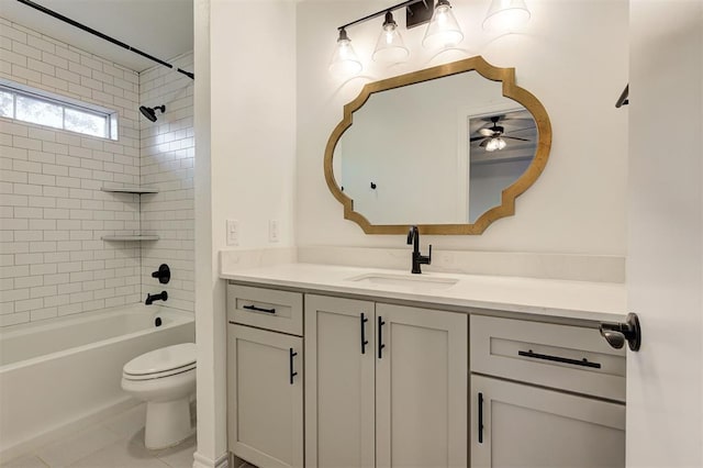 full bathroom with ceiling fan, tile patterned floors, toilet, vanity, and tiled shower / bath