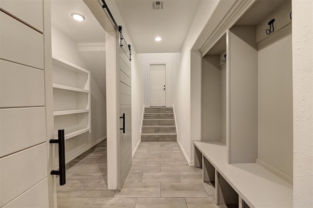 mudroom with a barn door and light wood-type flooring