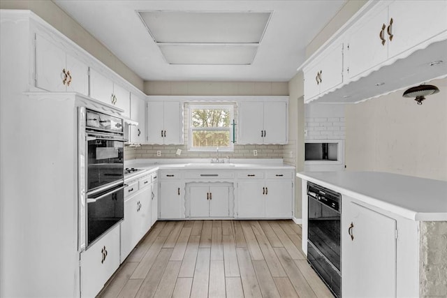 kitchen with white cabinets, decorative backsplash, and light hardwood / wood-style flooring