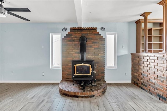 details featuring ceiling fan, beam ceiling, wood-type flooring, and a wood stove