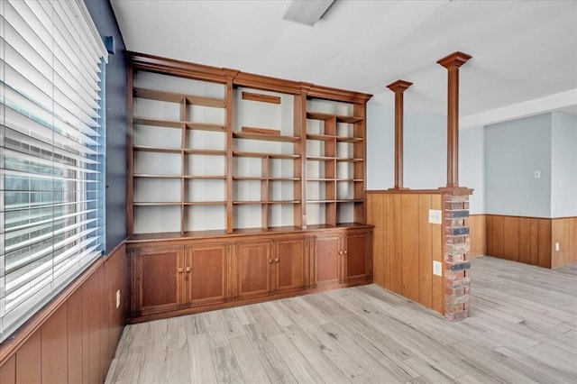 interior space featuring decorative light fixtures, wood walls, and light wood-type flooring