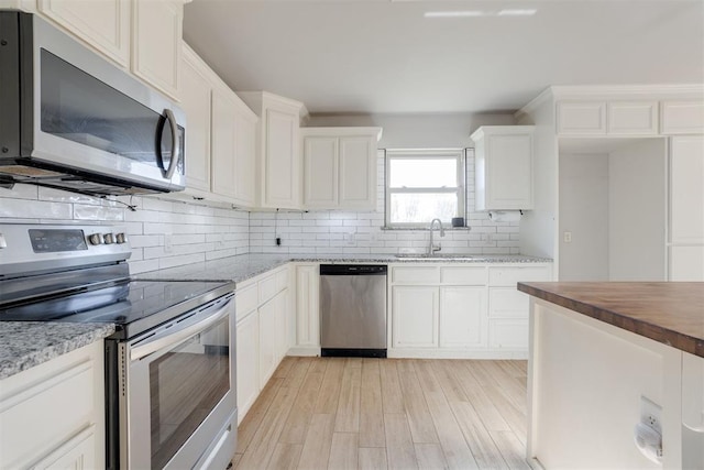 kitchen with wood counters, white cabinets, sink, appliances with stainless steel finishes, and light hardwood / wood-style floors