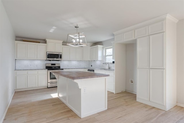 kitchen featuring a center island, hanging light fixtures, light hardwood / wood-style flooring, white cabinets, and appliances with stainless steel finishes