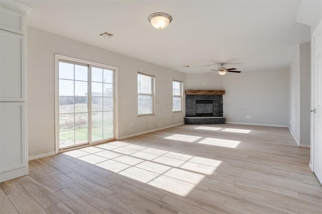 unfurnished living room with ceiling fan, light hardwood / wood-style floors, and a stone fireplace