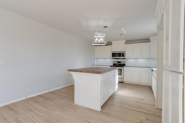 kitchen featuring stainless steel appliances, a kitchen island, white cabinetry, and light hardwood / wood-style floors