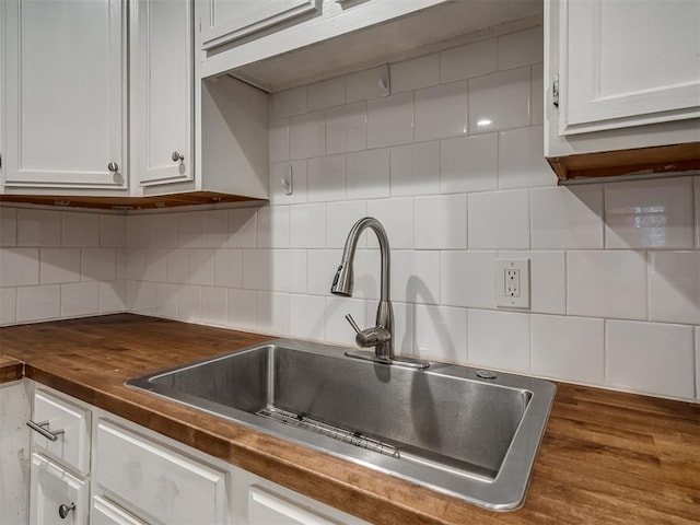 kitchen with backsplash, sink, hardwood / wood-style floors, butcher block countertops, and white cabinetry