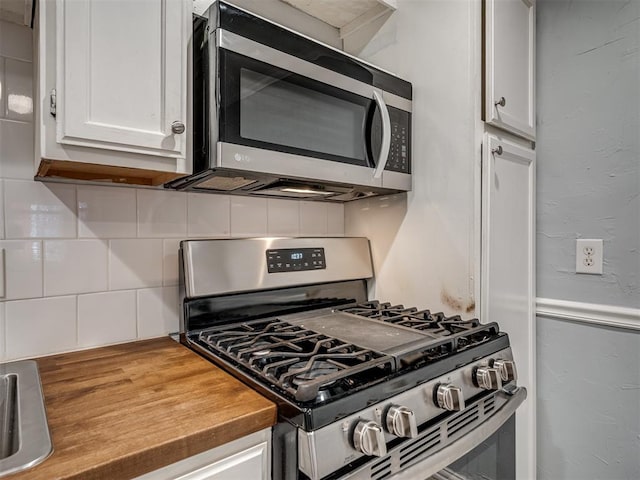 kitchen with white cabinets, backsplash, stainless steel appliances, and wooden counters