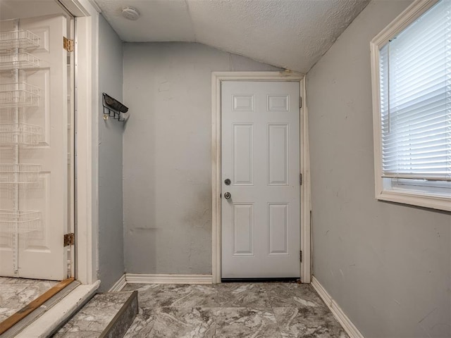 doorway to outside with a textured ceiling and vaulted ceiling