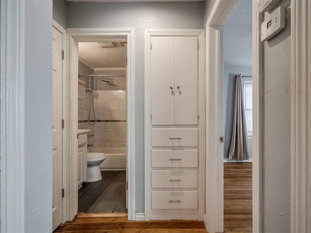 bathroom with toilet, wood-type flooring, and tiled shower / bath